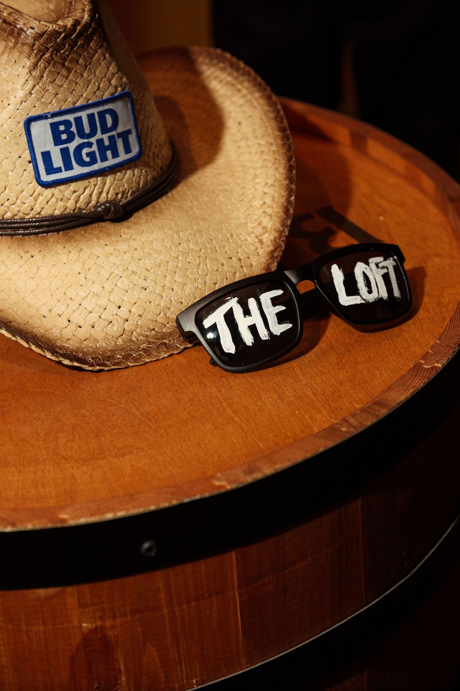 Bud Light branded straw cowboy hats displayed on wooden surface.