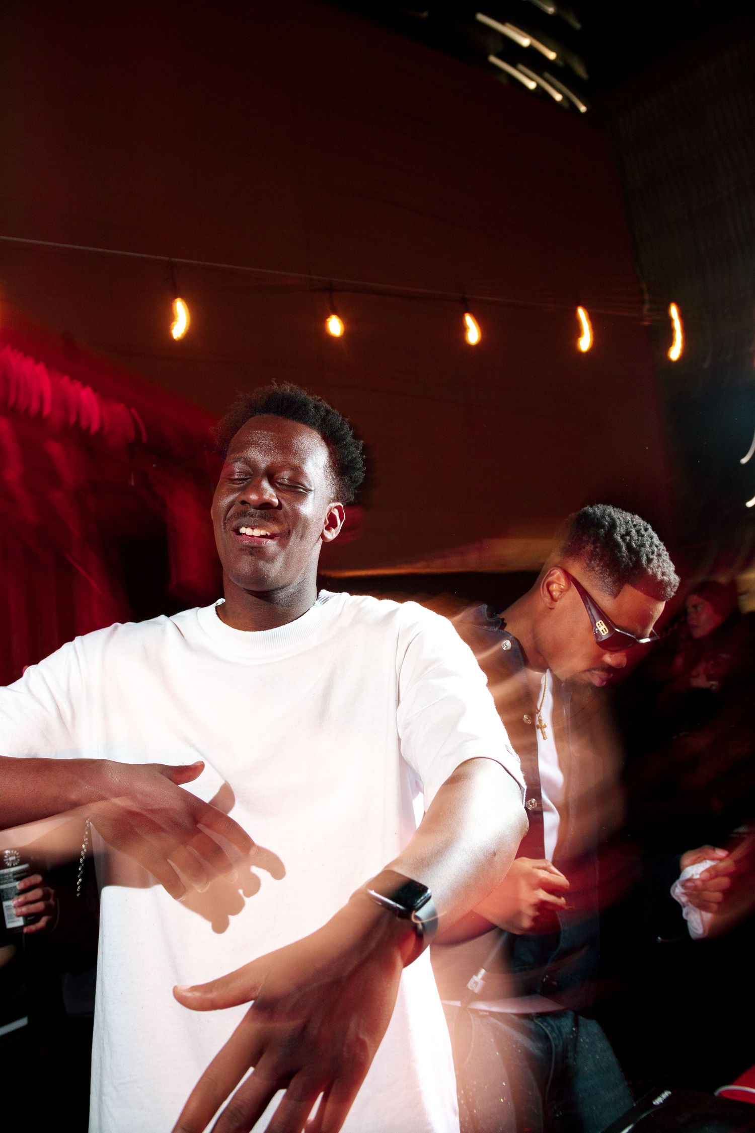Energetic performer in white shirt dancing at a nightclub event.