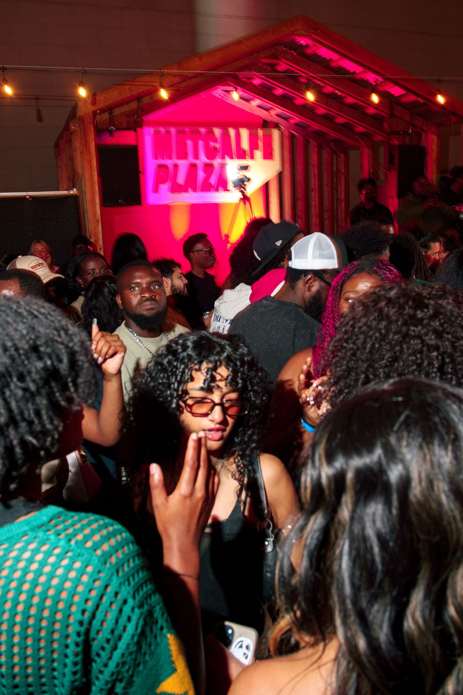 Crowded nightclub scene with pink lighting and party atmosphere.