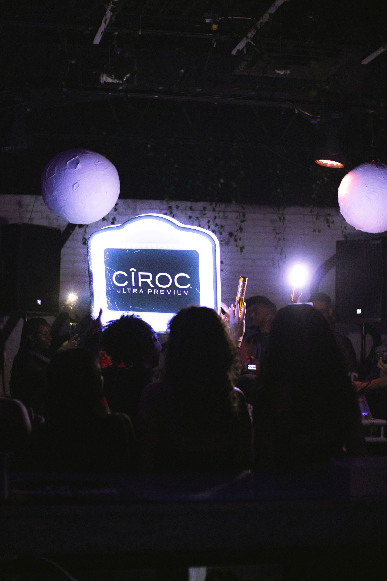 Illuminated Ciroc vodka sign and balloons create an atmospheric nightclub ambiance.