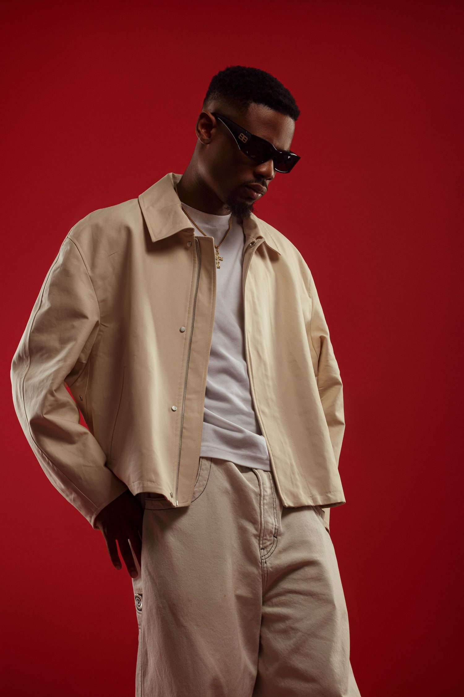 Fashion portrait of model in beige jacket against red background.