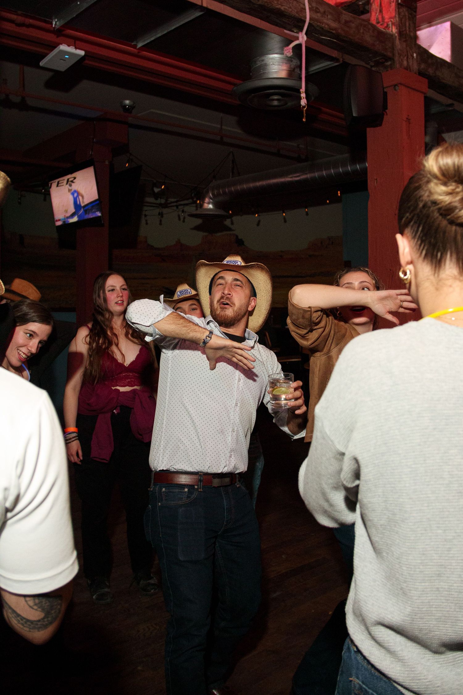 Group of people in white sweaters dancing together at a party.