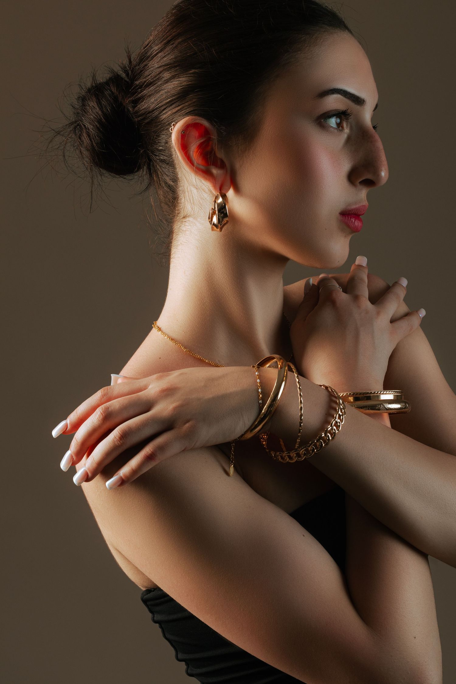 Artistic close-up portrait series focusing on jewelry and profile poses in dramatic lighting.