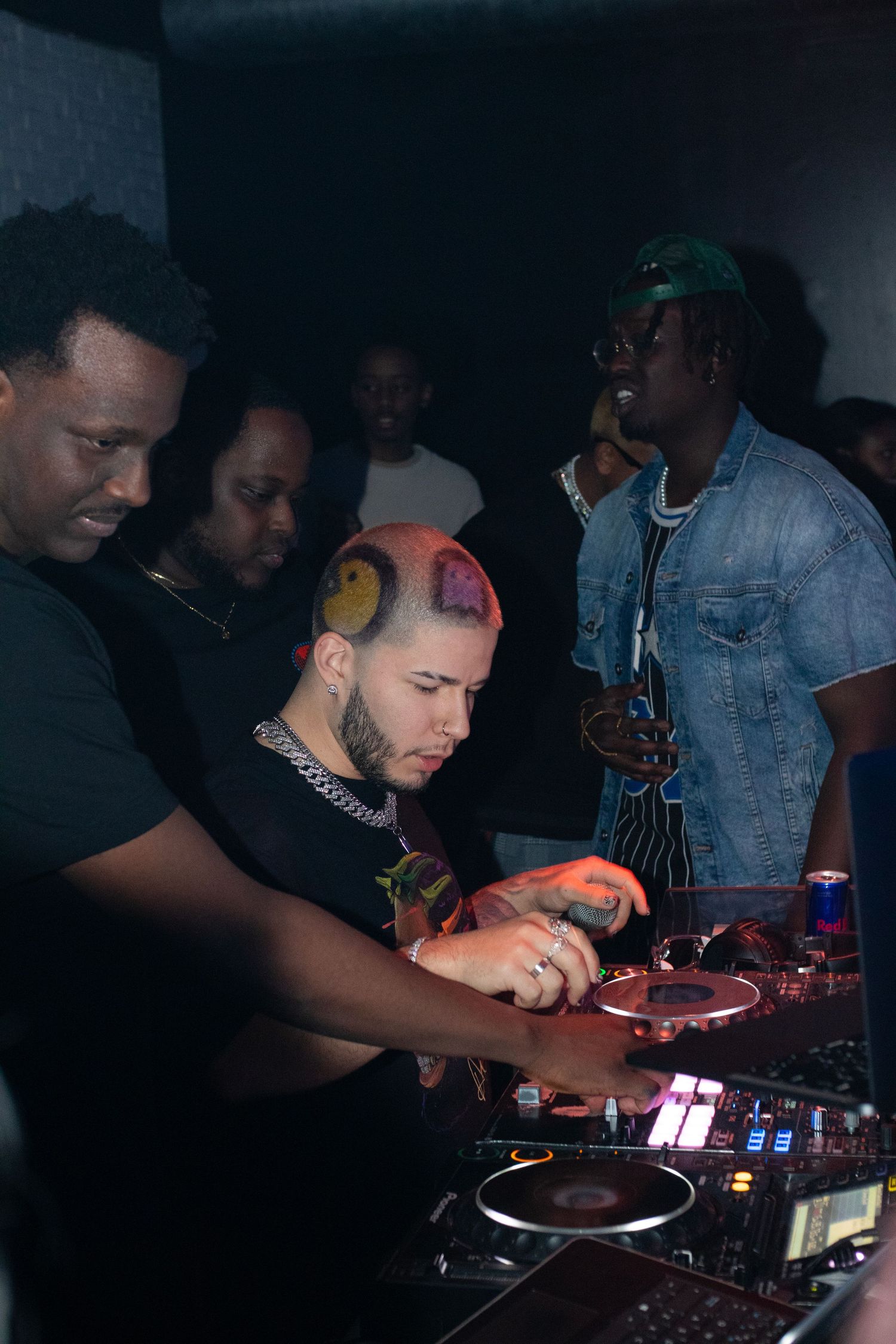 DJs perform at turntables in a dimly lit nightclub setting.