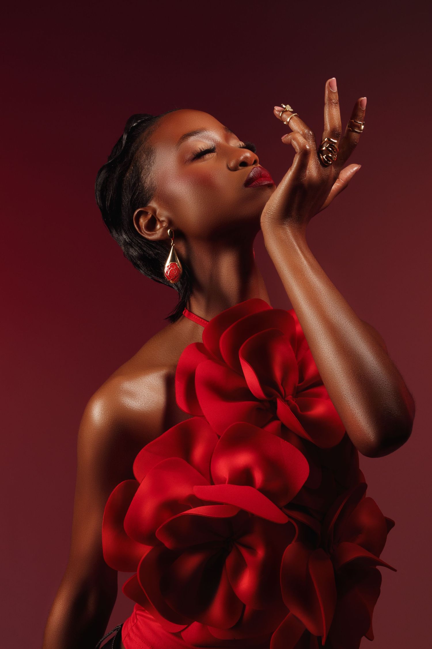Dramatic portrait with red floral details against burgundy background.
