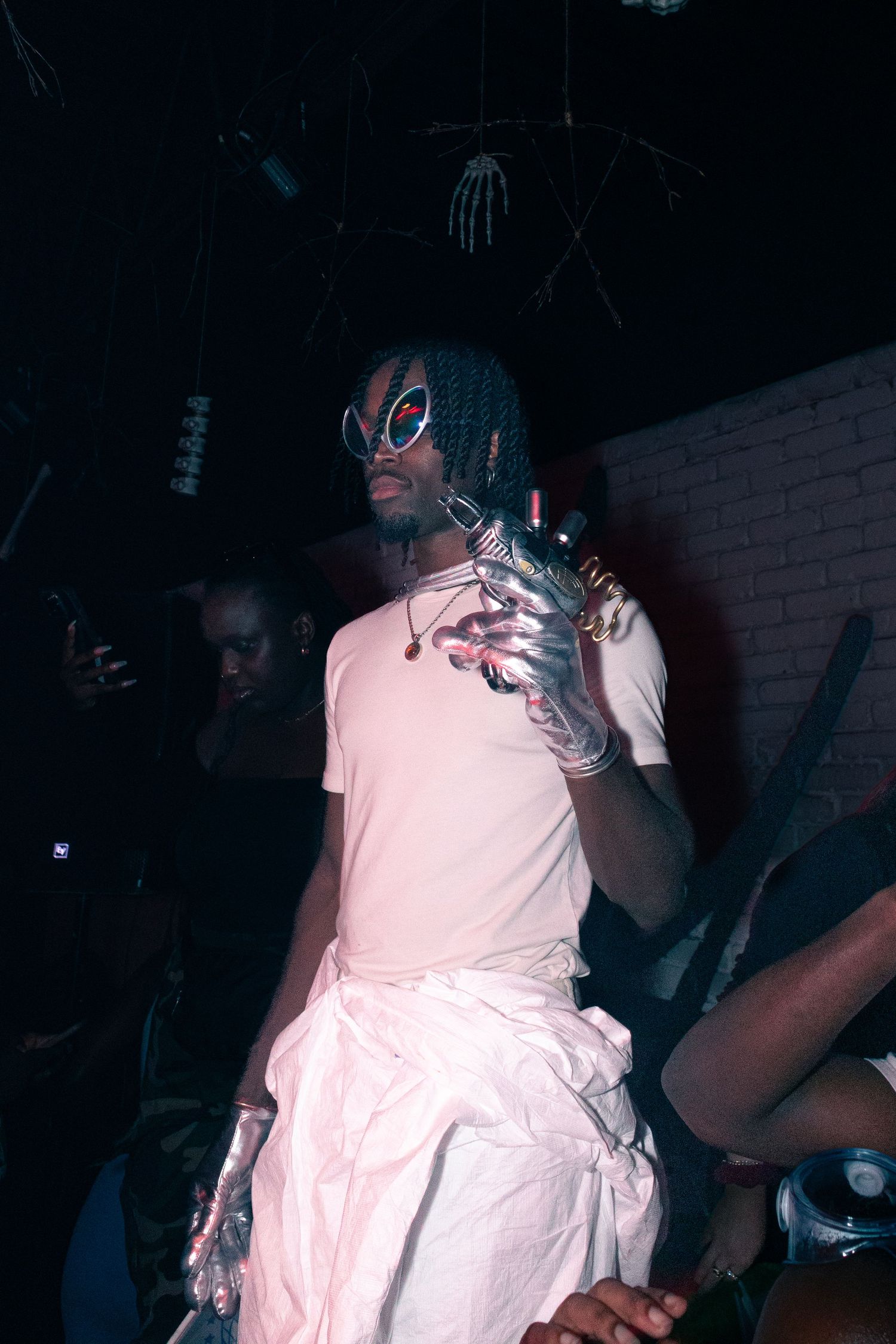 Person in white dress performing at a dimly lit nightclub event.