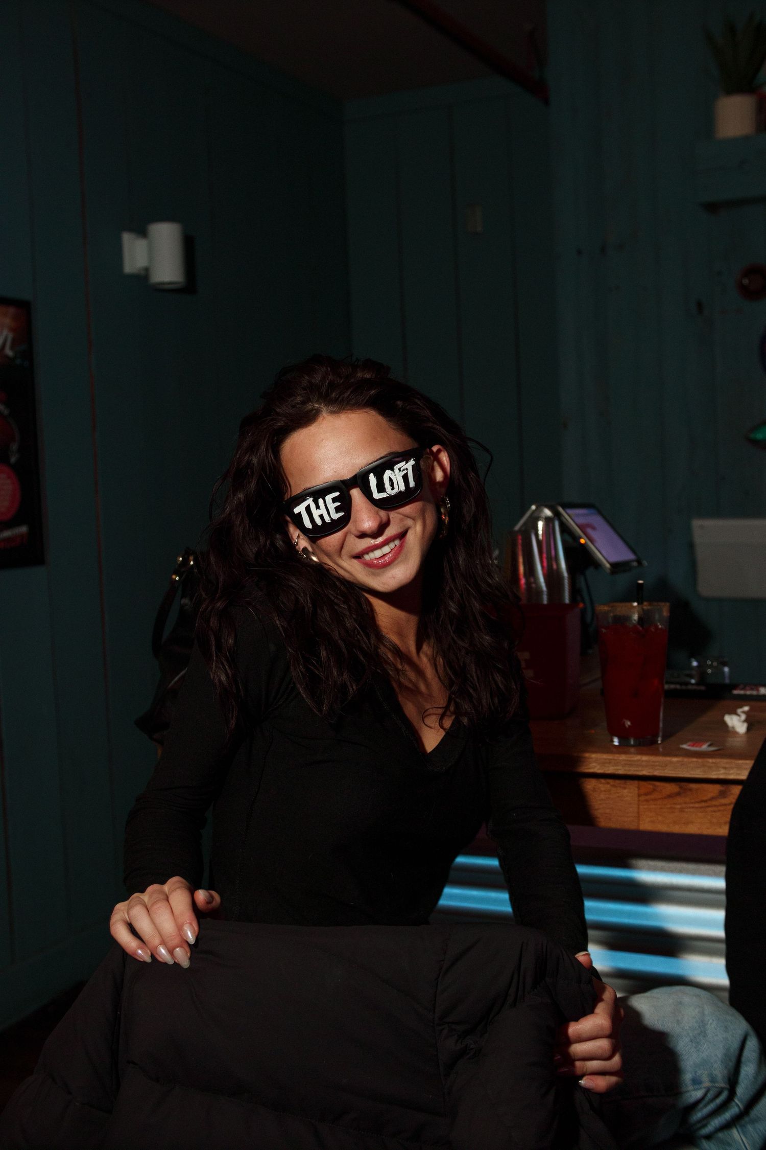 Dark silhouette wearing a branded headband in moody bar lighting.