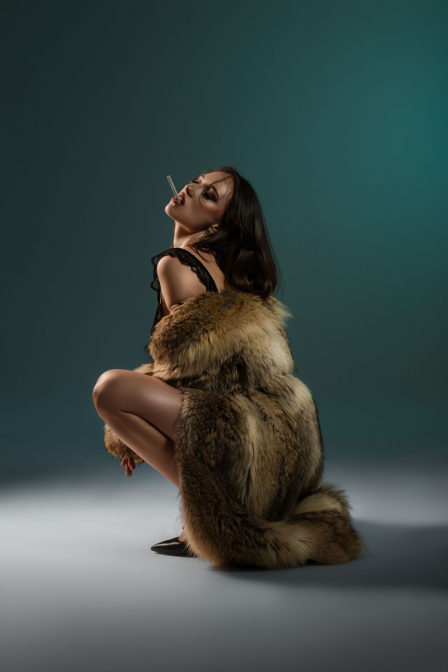 Artistic portrait with fur coat in moody lighting against teal background.