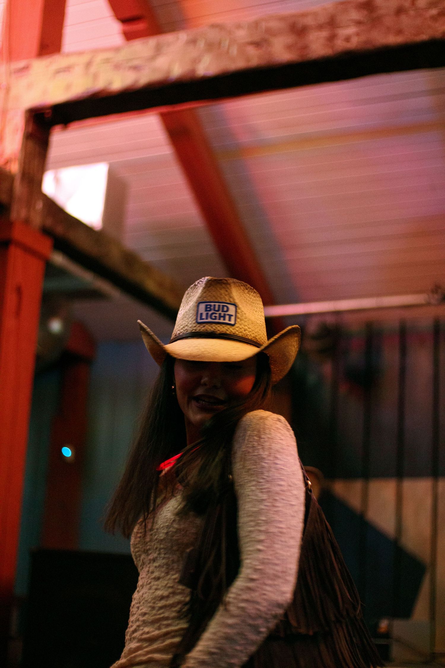 People in cowboy hats under red lighting at a bar event.