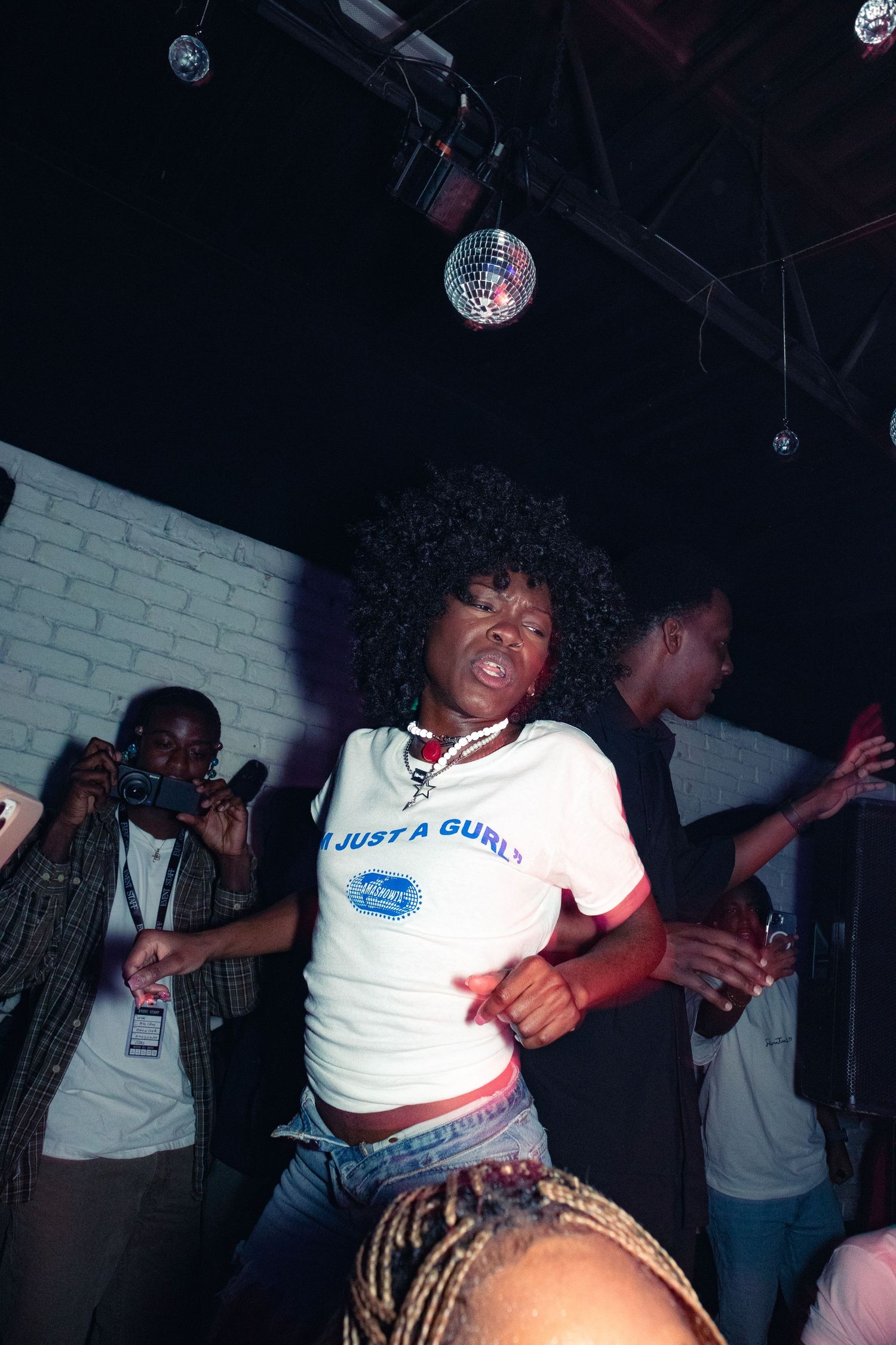 Group of people dancing at a nightclub under disco ball lighting.