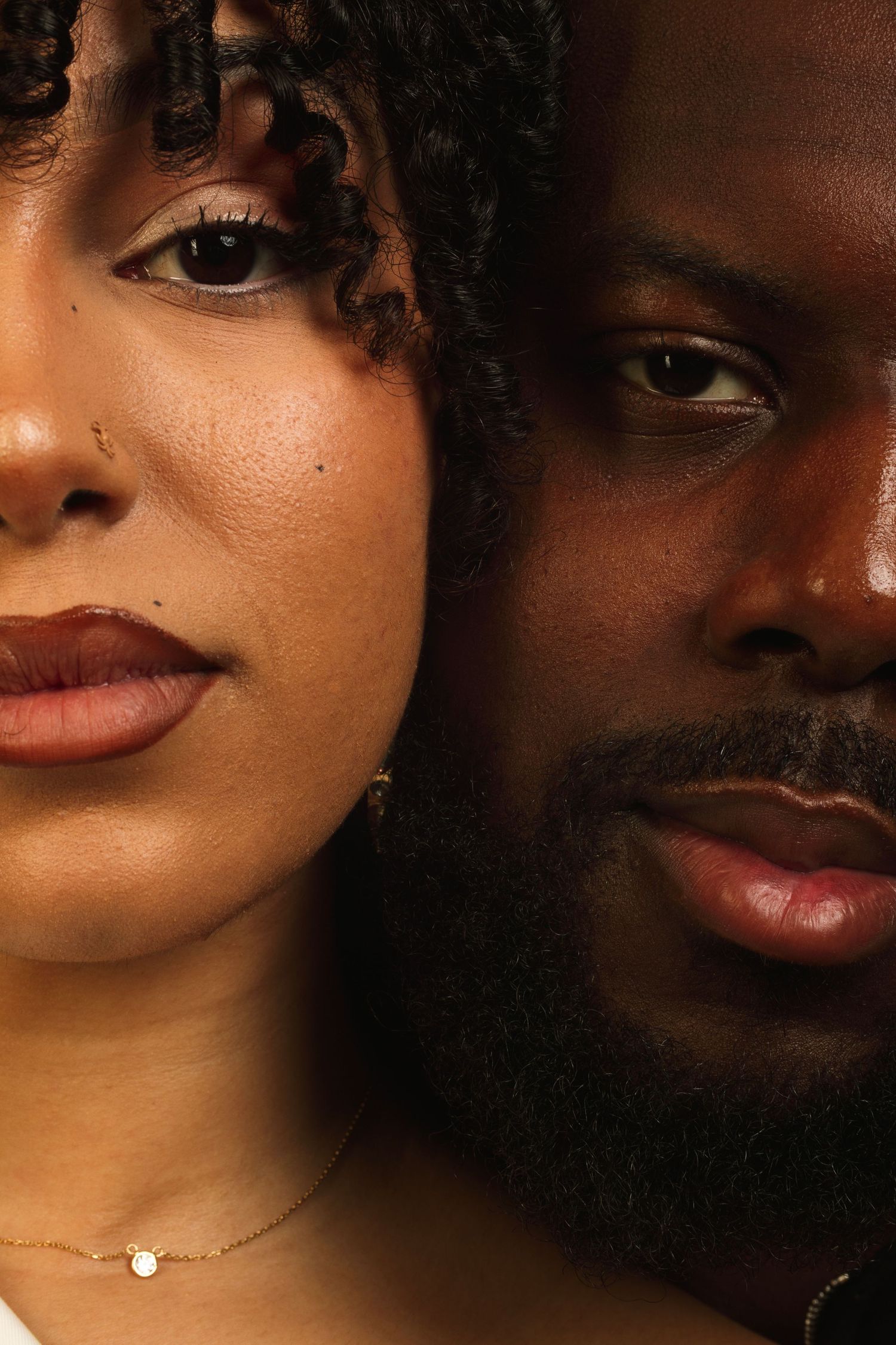 Close up beauty shot with glowing skin and natural makeup against dark background.