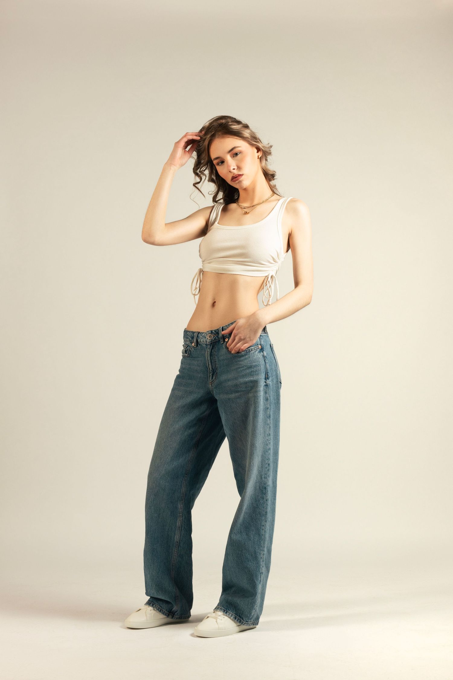 Fashion series showing casual poses in wide-leg jeans and crop top against neutral background.