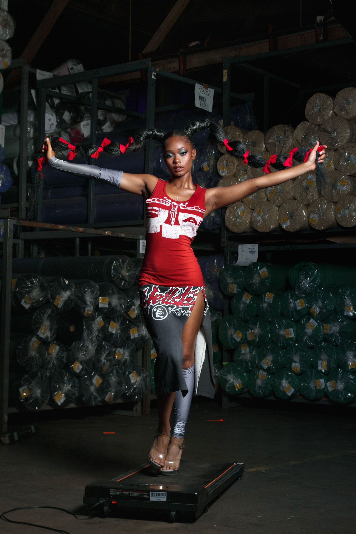Dancer in red athletic wear performs on exercise platform surrounded by storage.