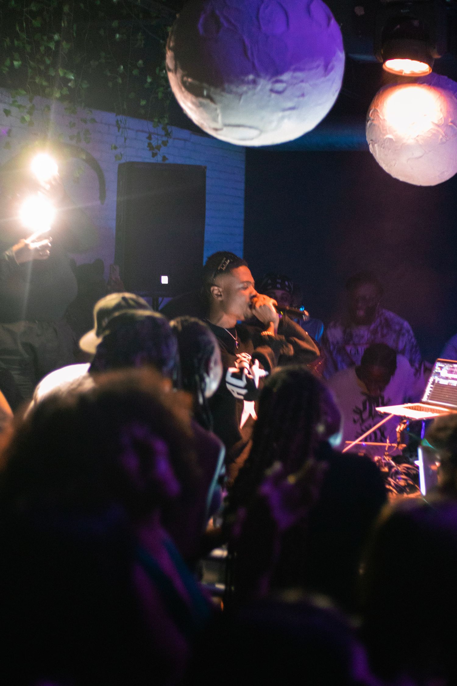 Energetic performance on stage with large decorative spheres and purple lighting.