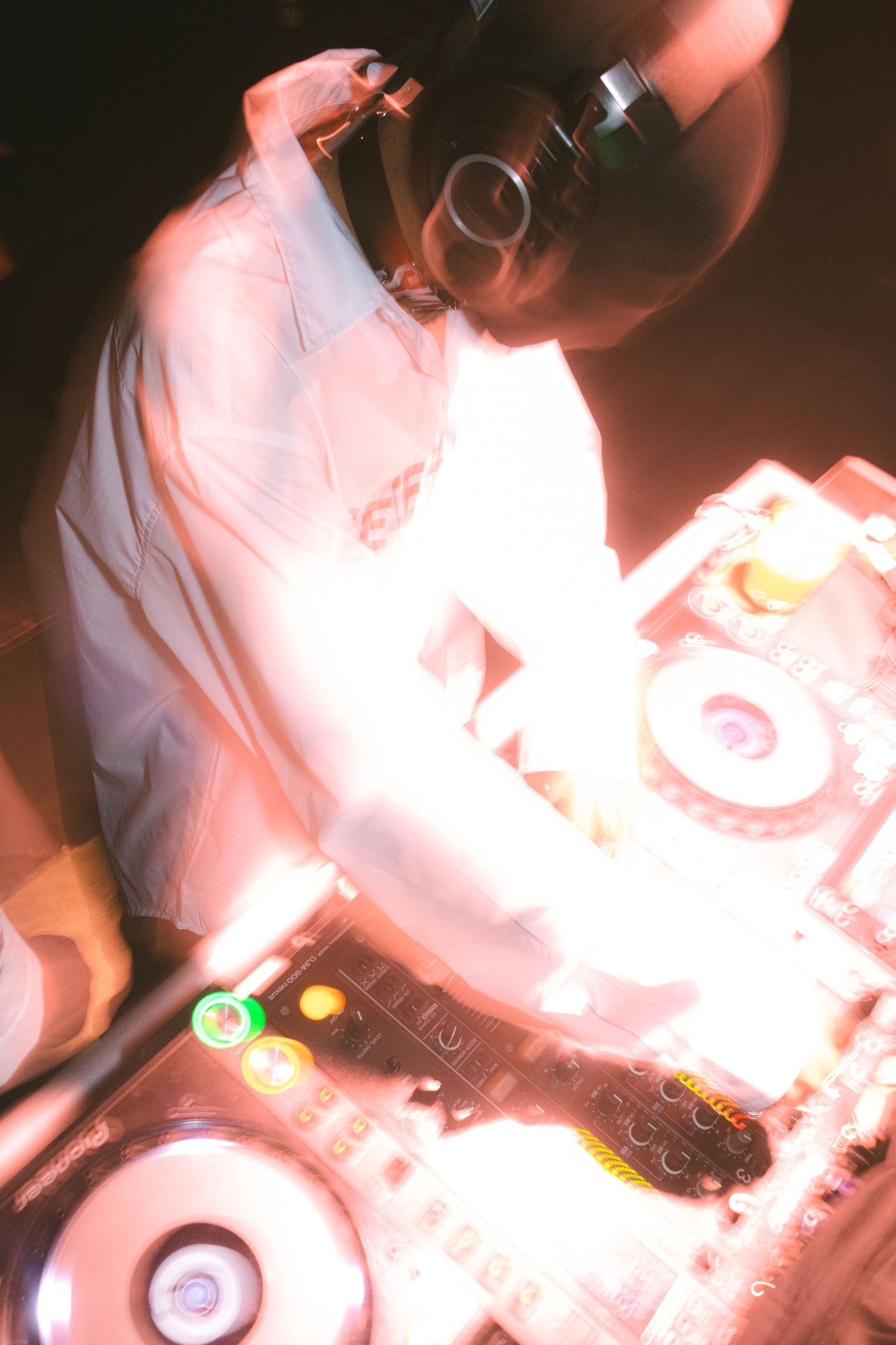 DJ mixing music on turntables under warm red lighting.