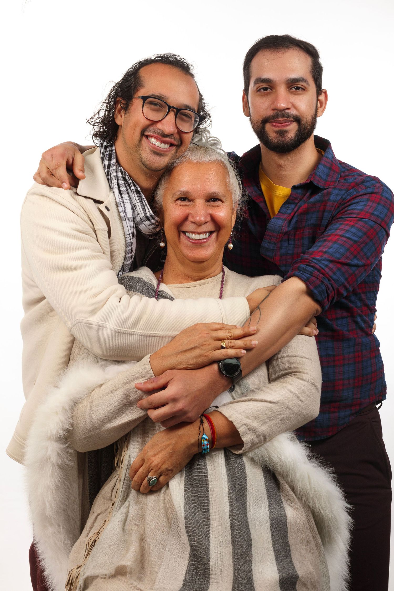 Three people embracing and smiling warmly against white background.