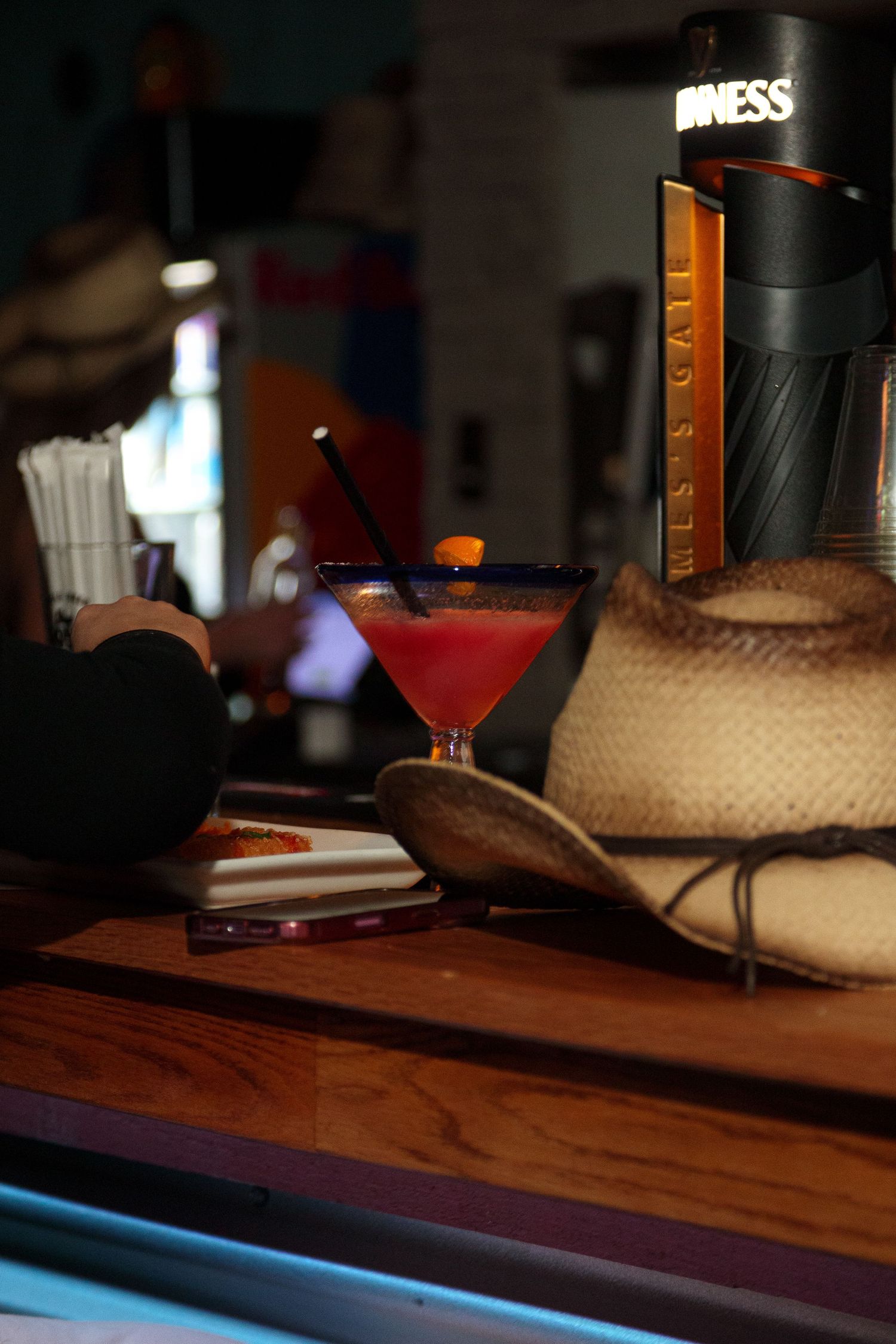 Cocktail glasses and bottles arranged on a wooden bar counter with ambient lighting.
