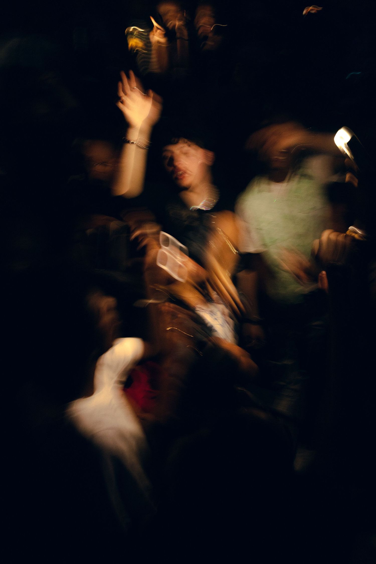 Blurred motion of people dancing in a dark nightclub setting.