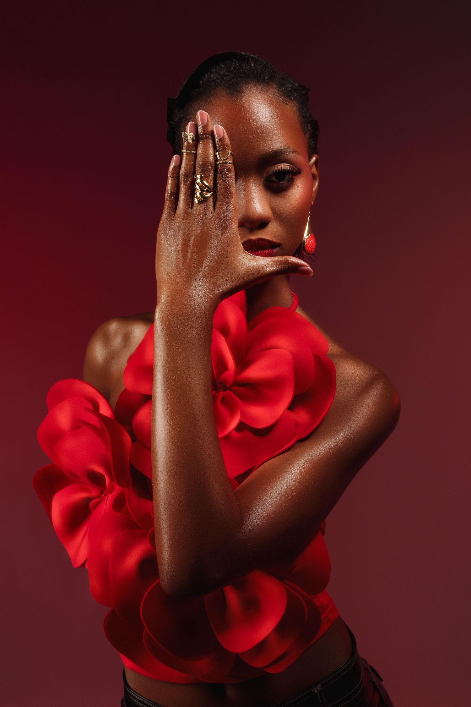 Dramatic portrait with red ruffled top against dark burgundy background.