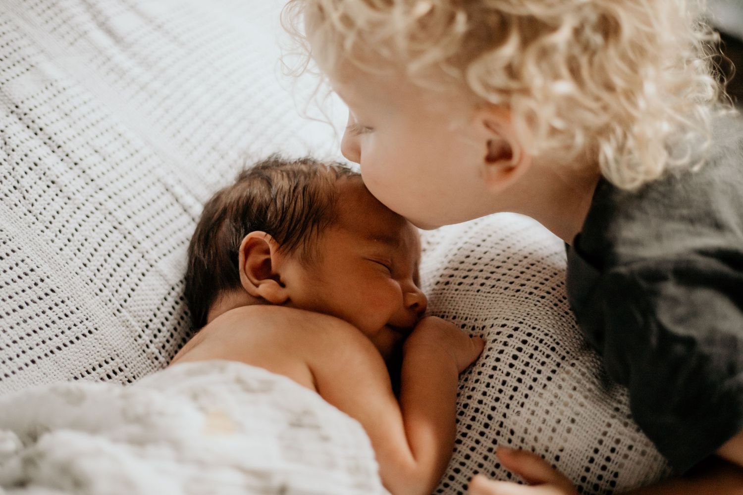 A sleeping baby wrapped in a cozy white knit blanket rests peacefully.