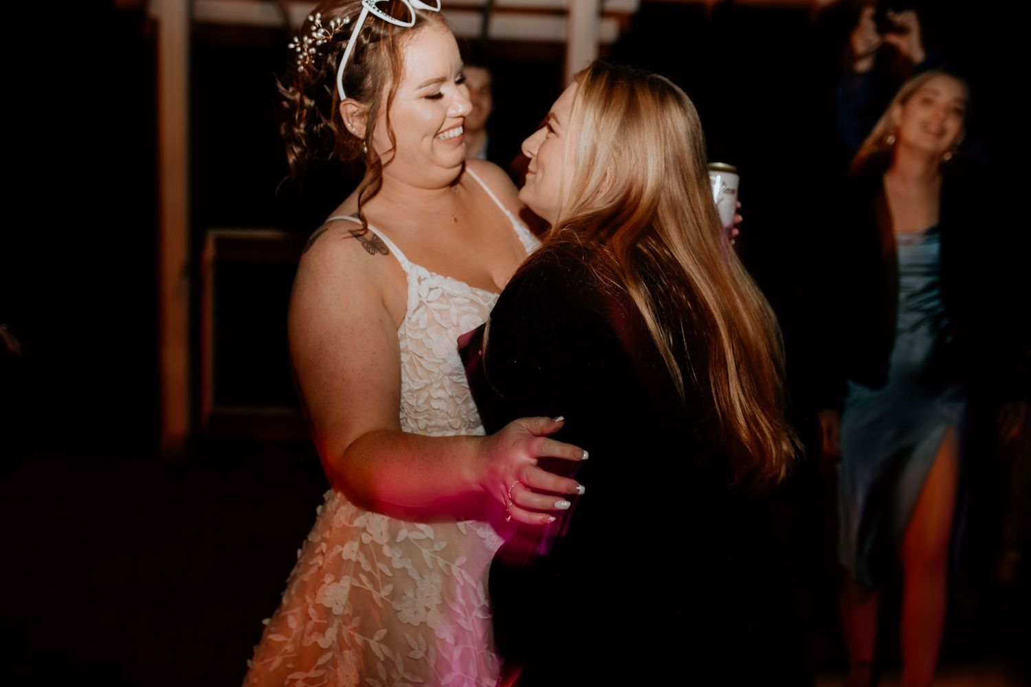 Wedding reception dance floor scene with guests dancing in a dimly lit venue.