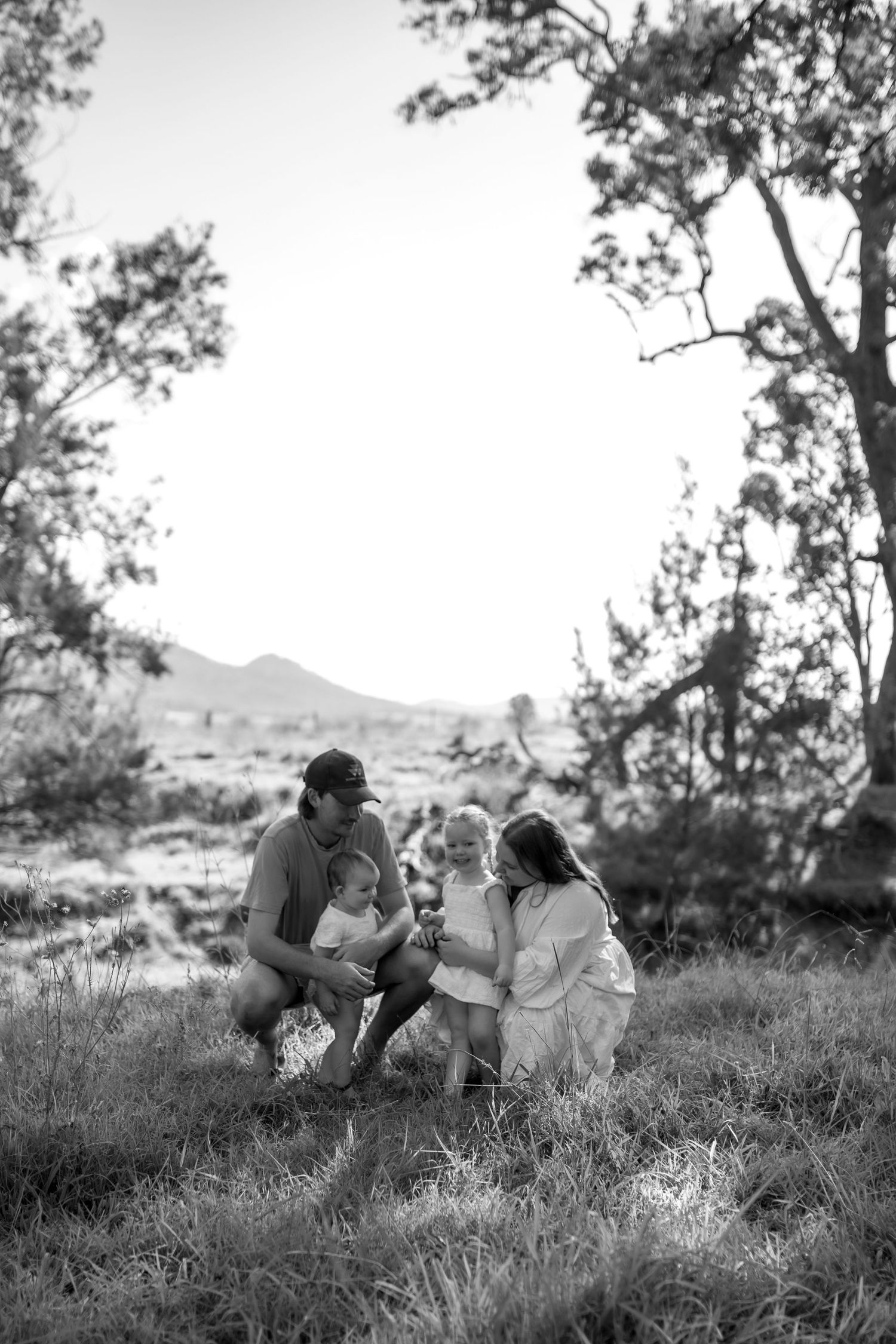Romantic couple's photoshoot on a grassy hillside at sunset.