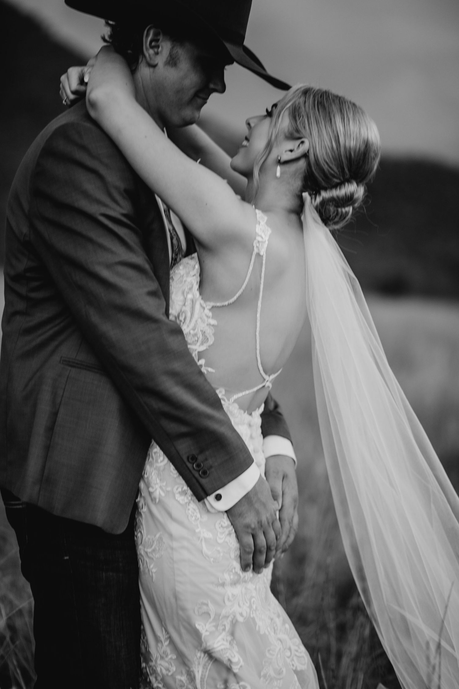 Dramatic black and white portrait of romantic wedding embrace with flowing veil.