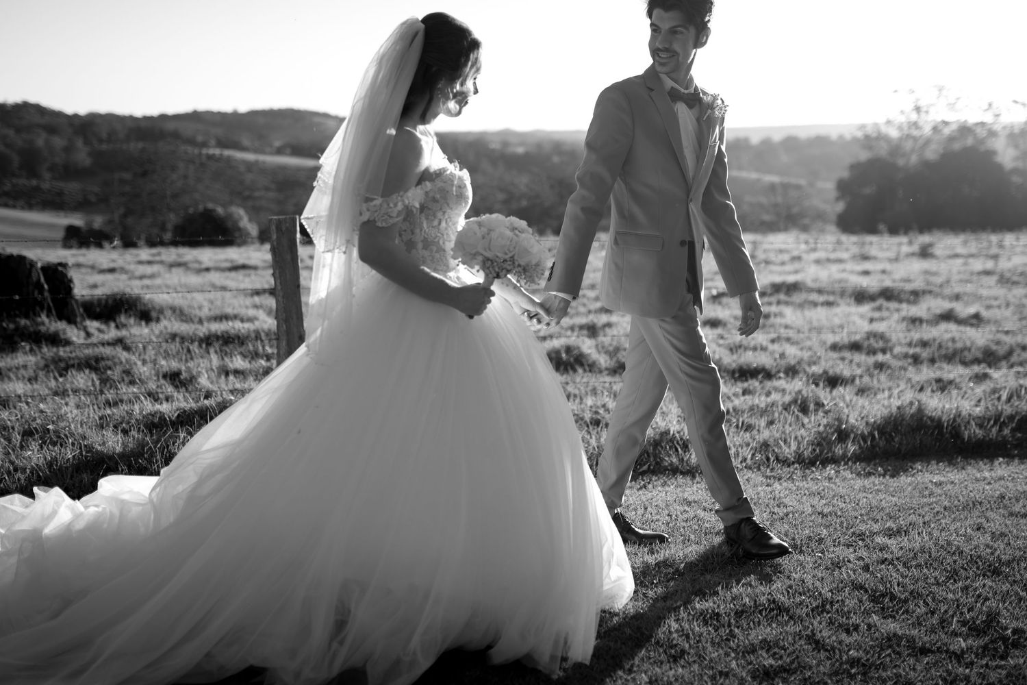 Silhouettes of a wedding couple in a sunlit outdoor field.