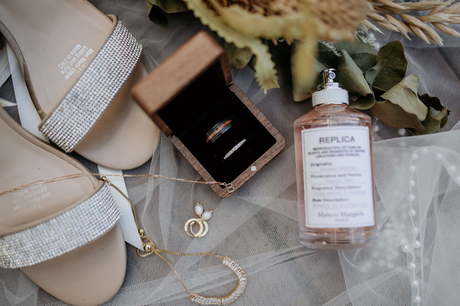 Wedding details including sparkly shoes, rings, and perfume bottle arranged on a surface.