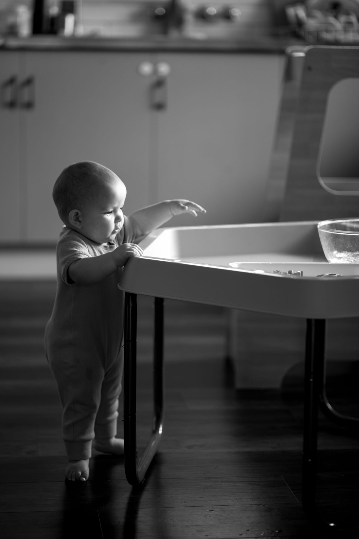 Black and white sequence showing a small child reaching up to explore a table edge.