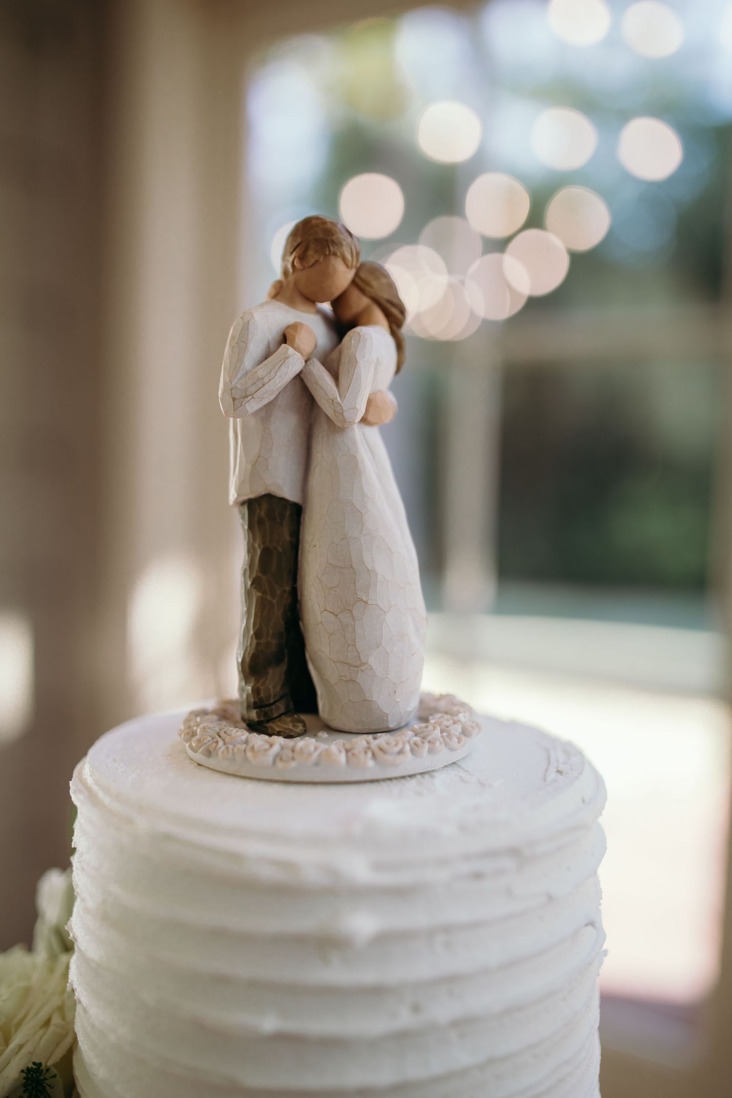 Simple white wedding cake topped with minimalist ceramic figurines.