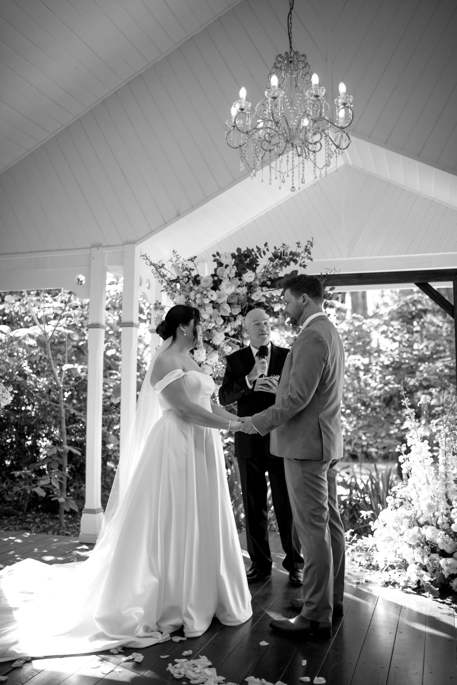 A black and white series of wedding ceremony moments captured under a covered outdoor venue with chandeliers.