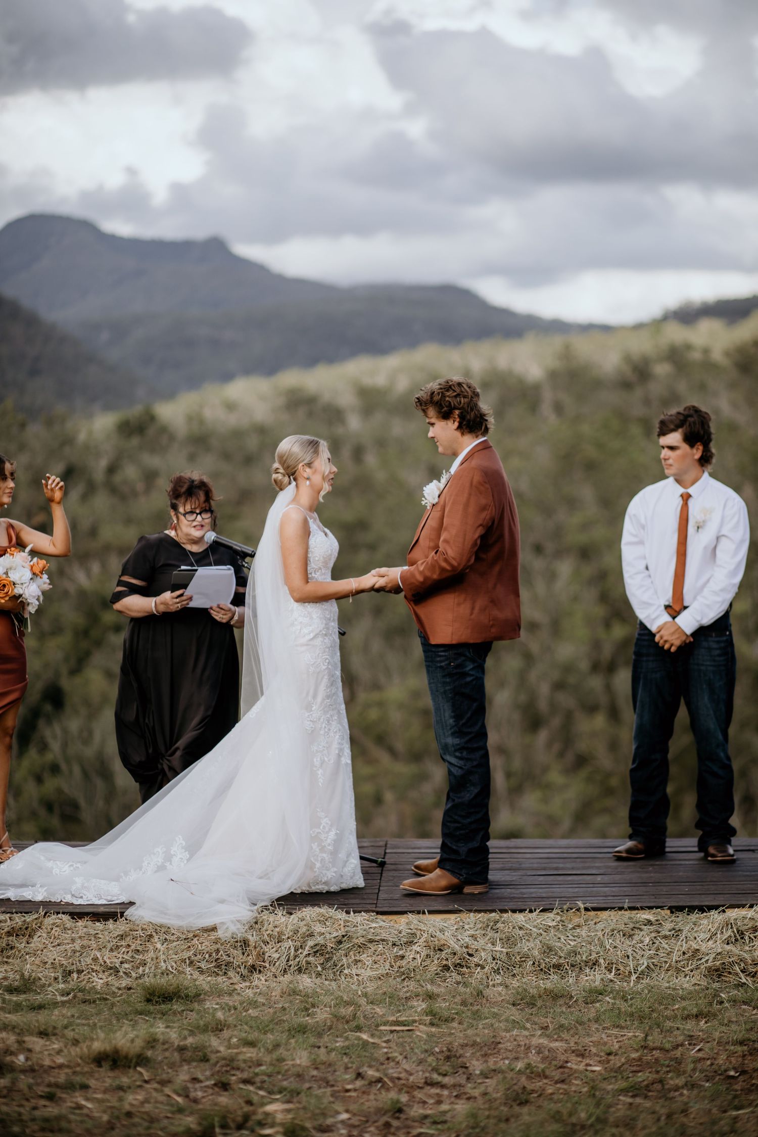 Outdoor mountain wedding ceremony with dramatic cloudy sky backdrop.