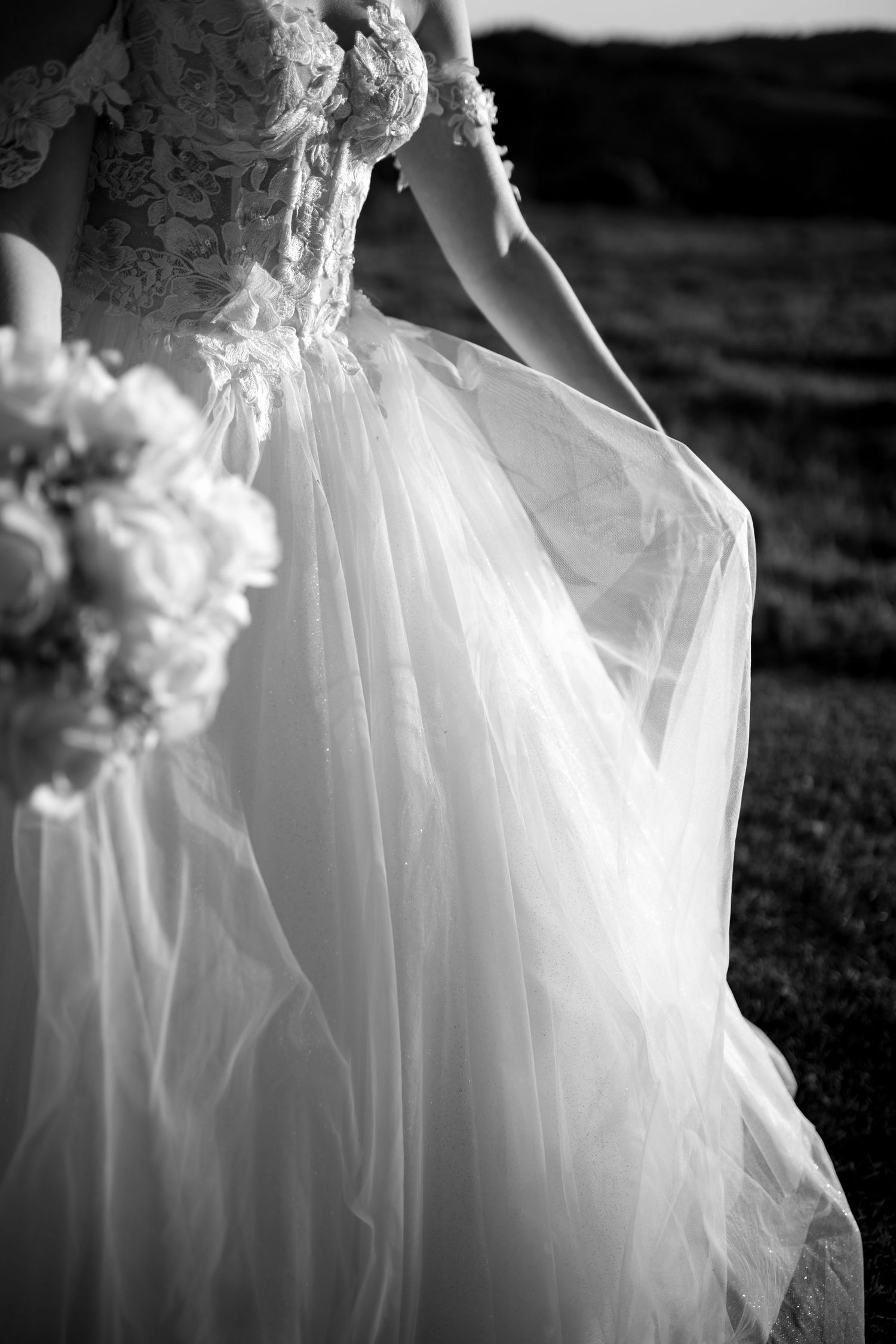 Flowing white wedding dress fabric creates an ethereal silhouette against a dark background.