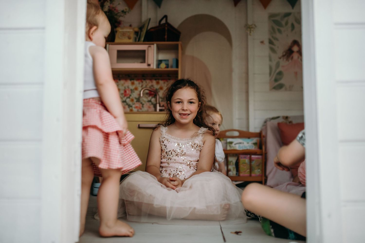 Interior view through a white doorway into a decorated playroom with soft pink accents.