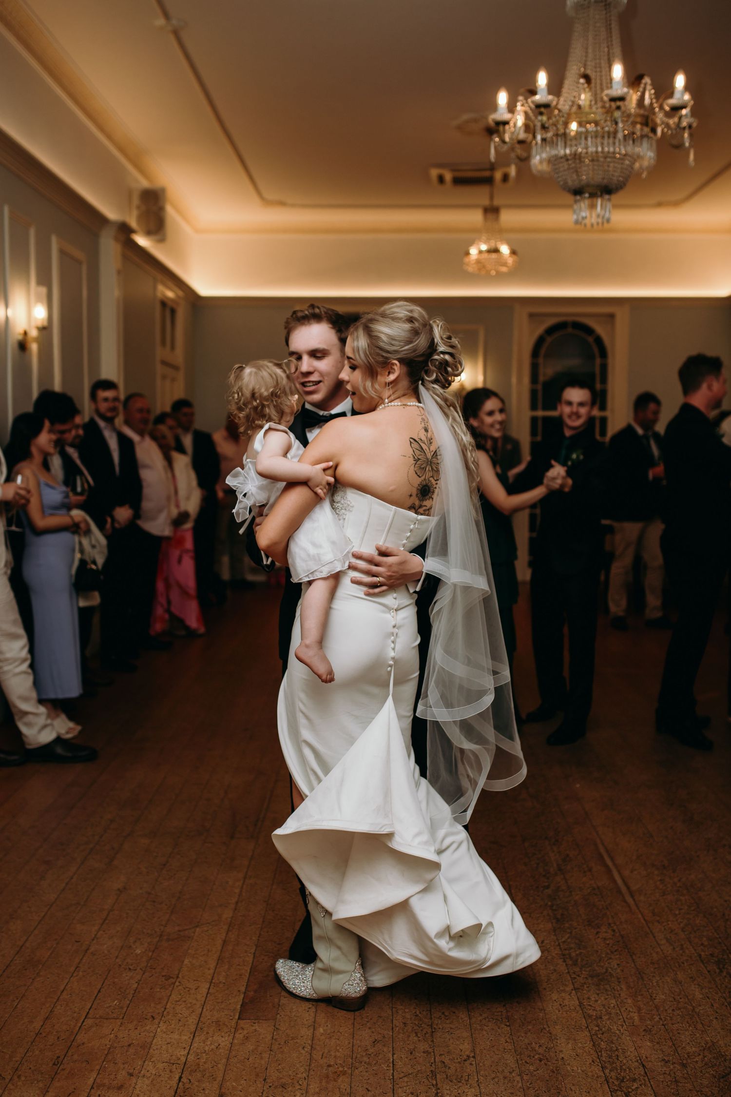 Wedding couple performs a dip dance move on a wooden ballroom floor.