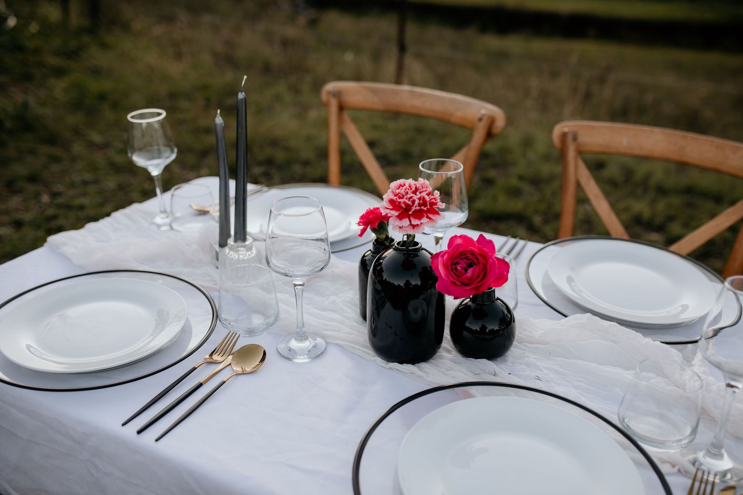 Elegant wedding table settings with white plates, wine glasses, and wooden chairs.