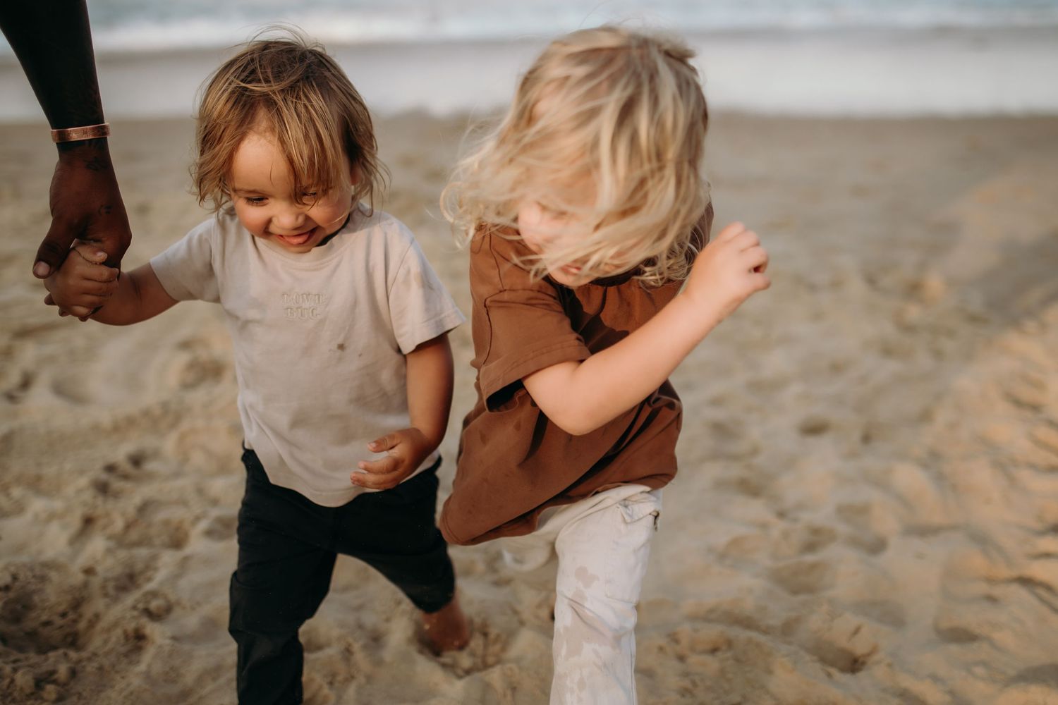 Children playing together on a sandy beach during golden hour.