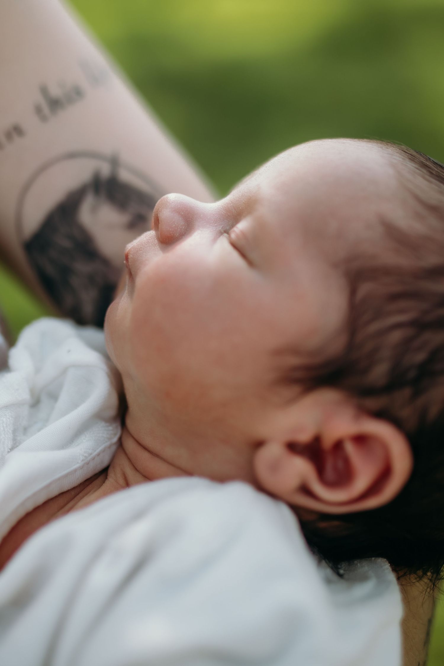 Close-up profile view of a sleeping baby in white clothing.