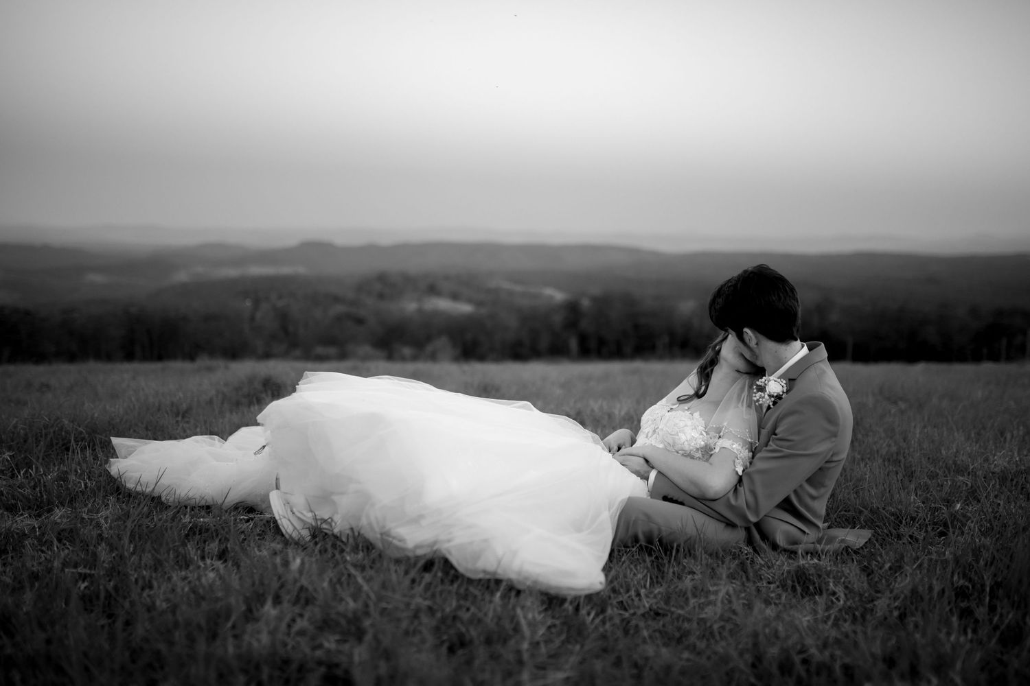 A black and white photo series showing a person in a white dress lying down in a grassy field at different angles.