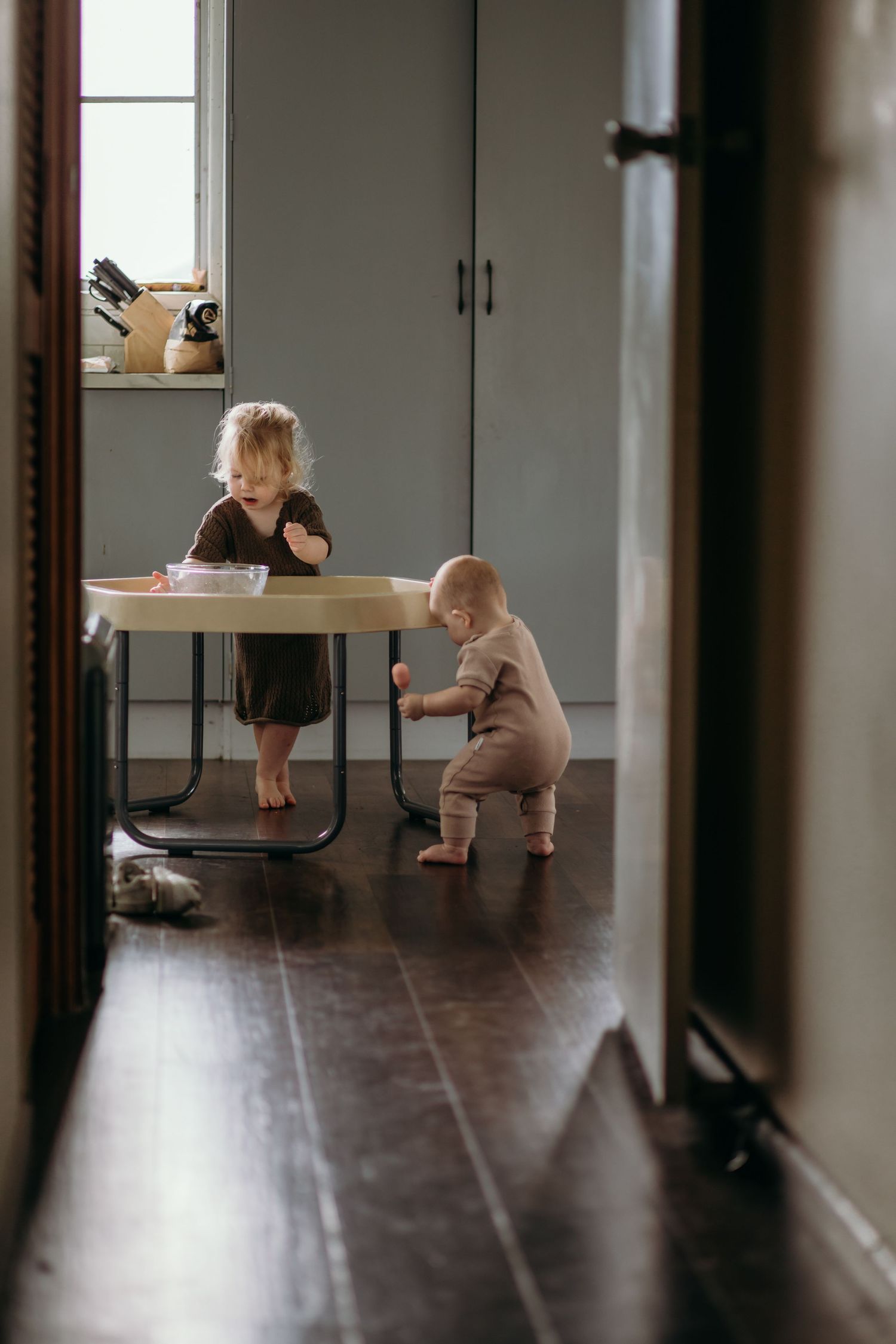 Interior view of a room with hardwood floors showing a small figure exploring near furniture.