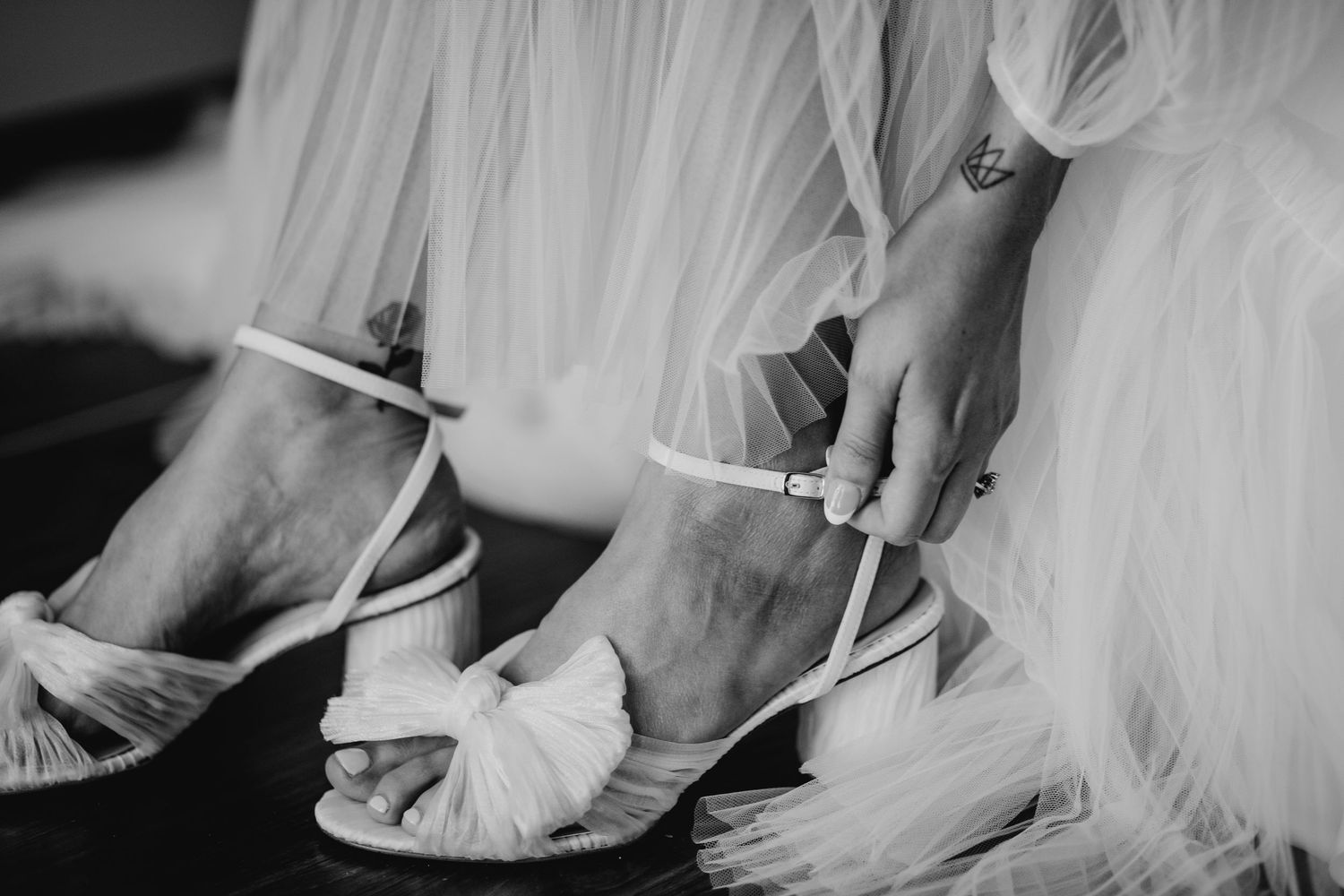 Close-up details of a bride's shoes and wedding dress hem with delicate lace.
