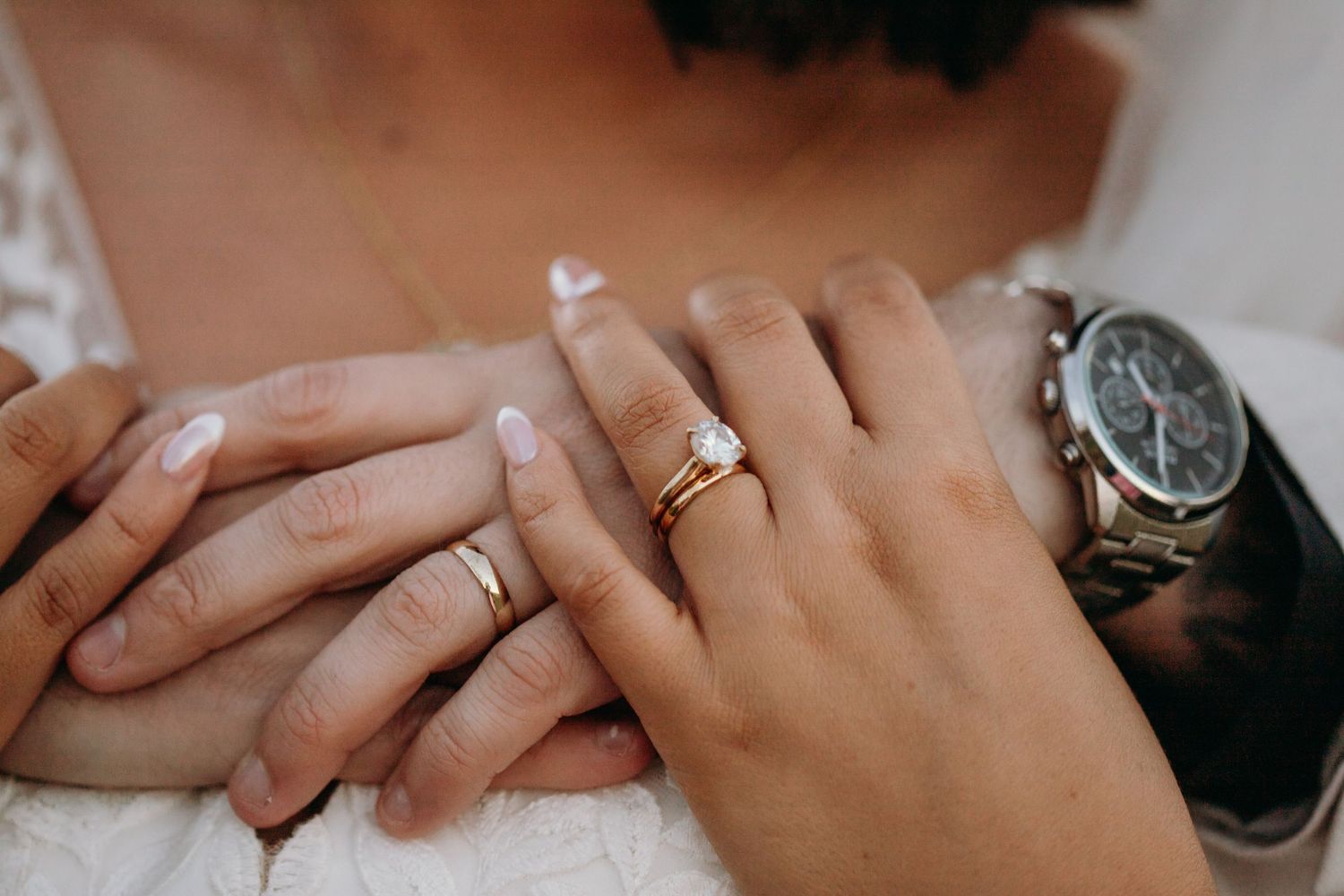 Close-up of wedding rings and hands showing newly married couple's jewelry.