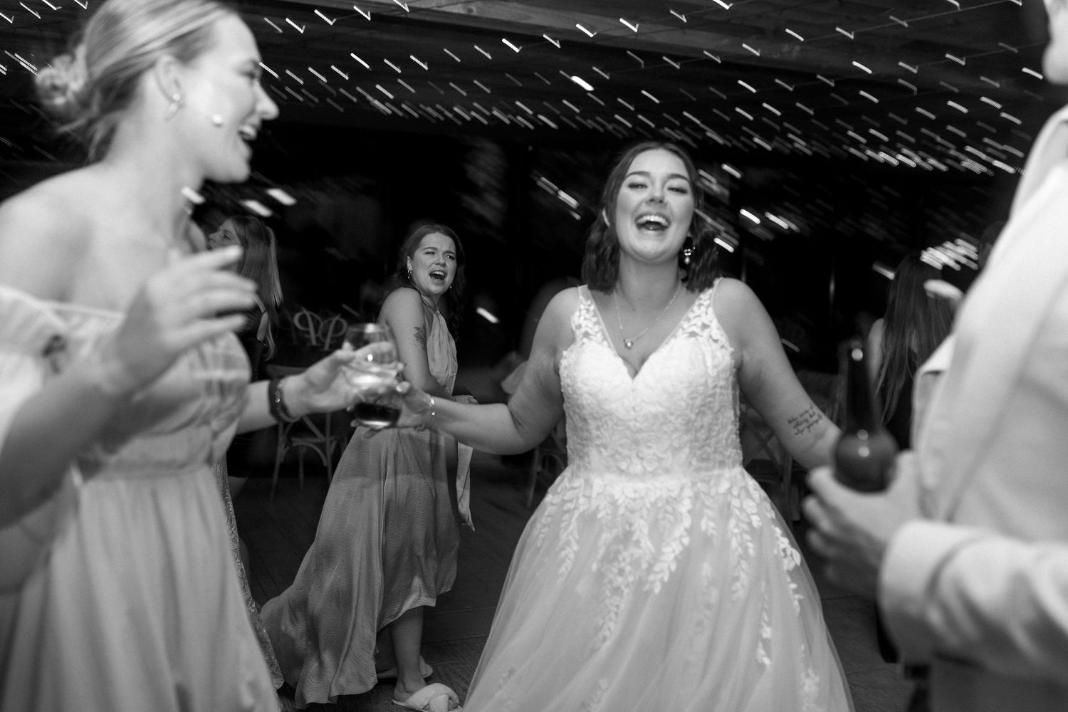 A joyous celebration on the dance floor at a wedding reception with bridesmaids and the bride dancing together.