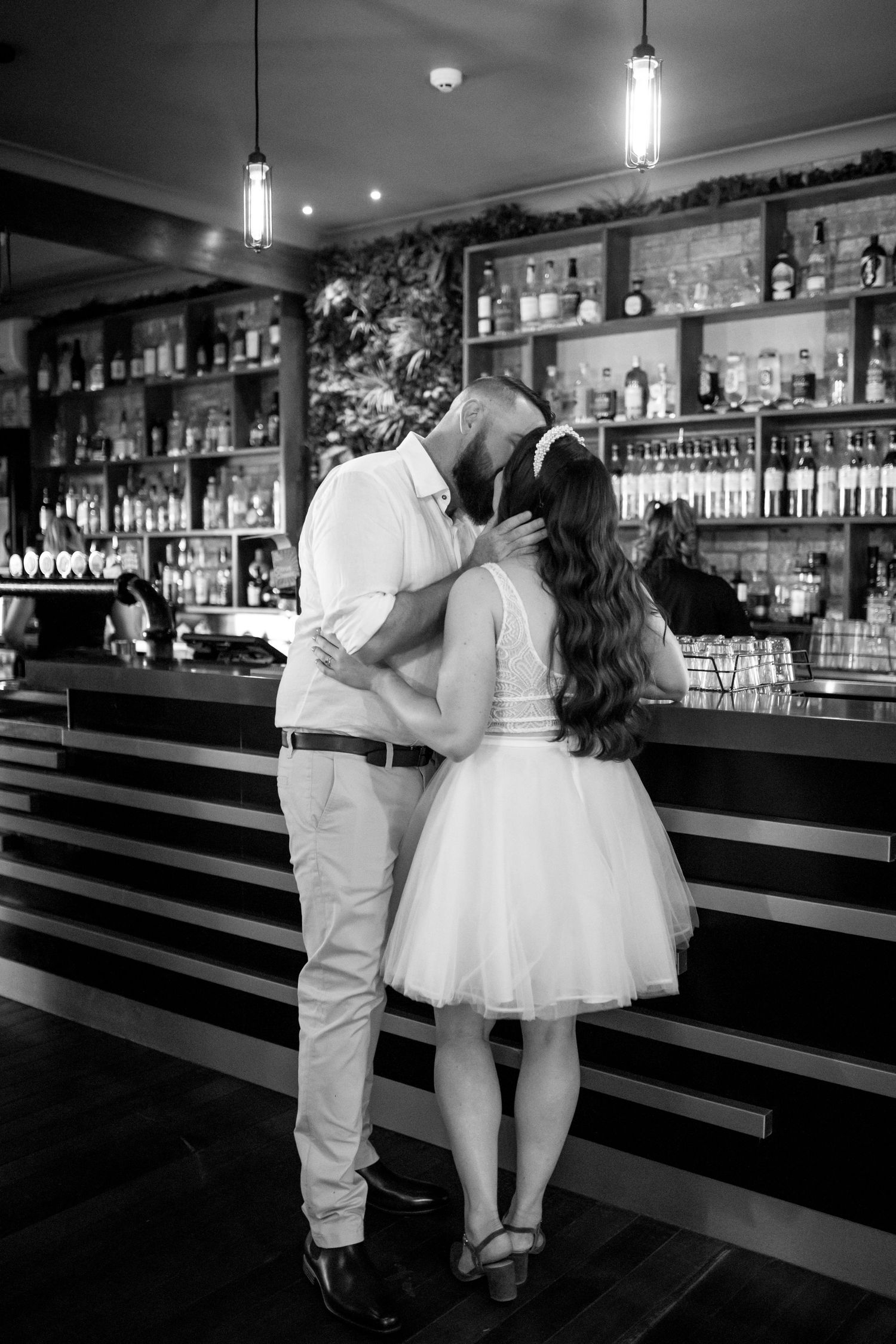 Wedding couple sharing romantic moments at a stylish bar counter in black and white.