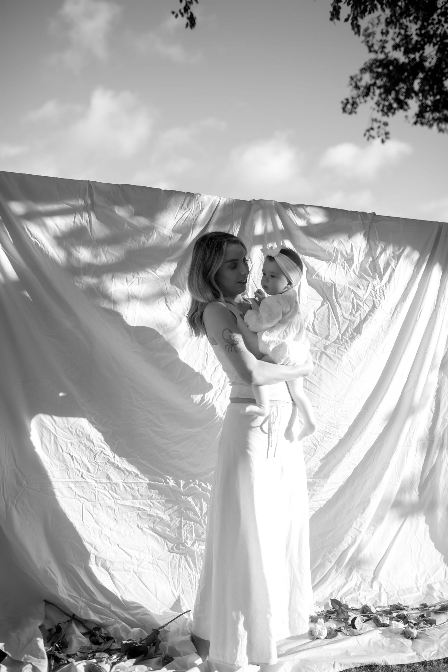 Parent and infant silhouetted against a white backdrop in an artistic black and white photograph.