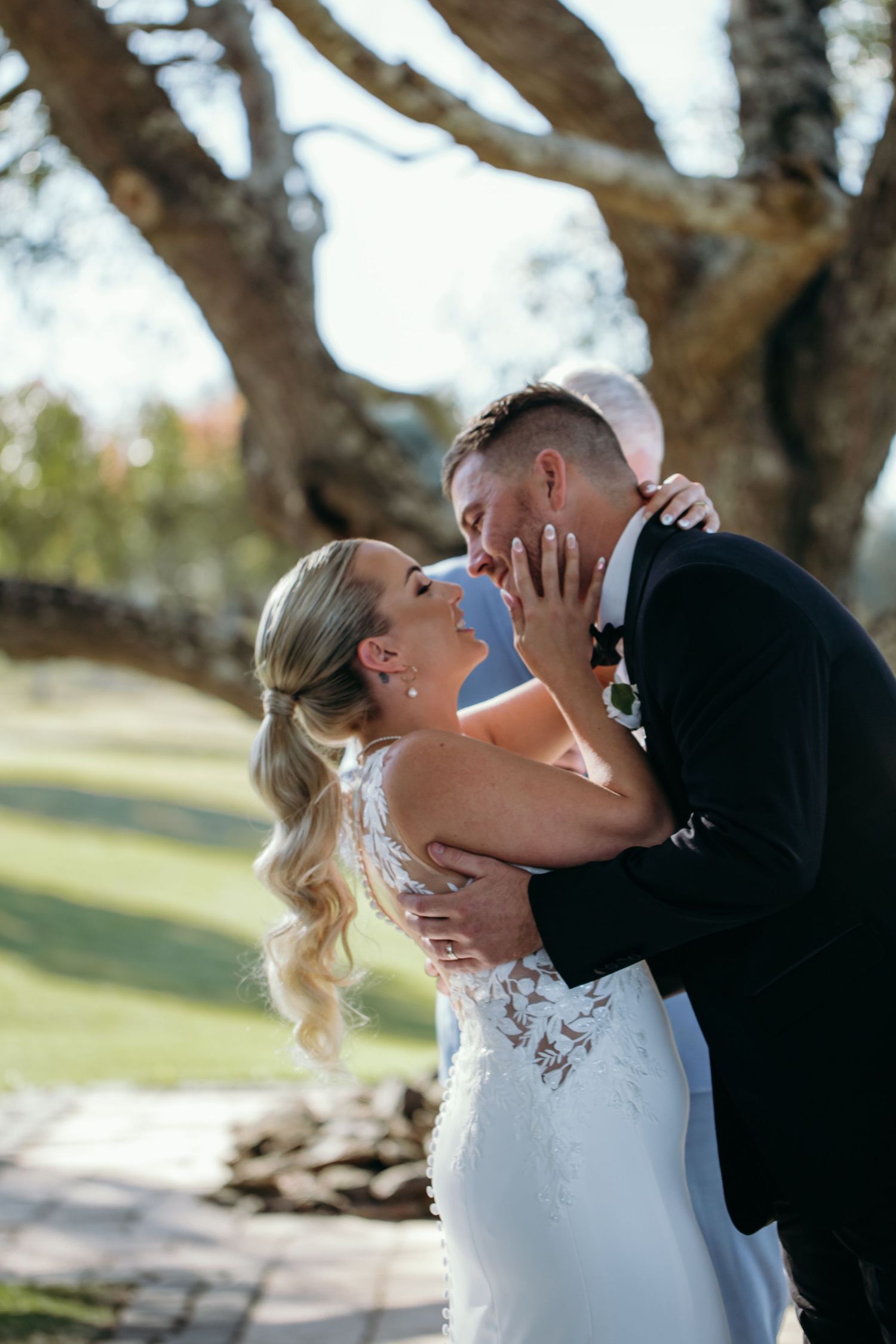 A romantic sequence of wedding photos showing a couple sharing a tender kiss under blooming trees in a park setting.