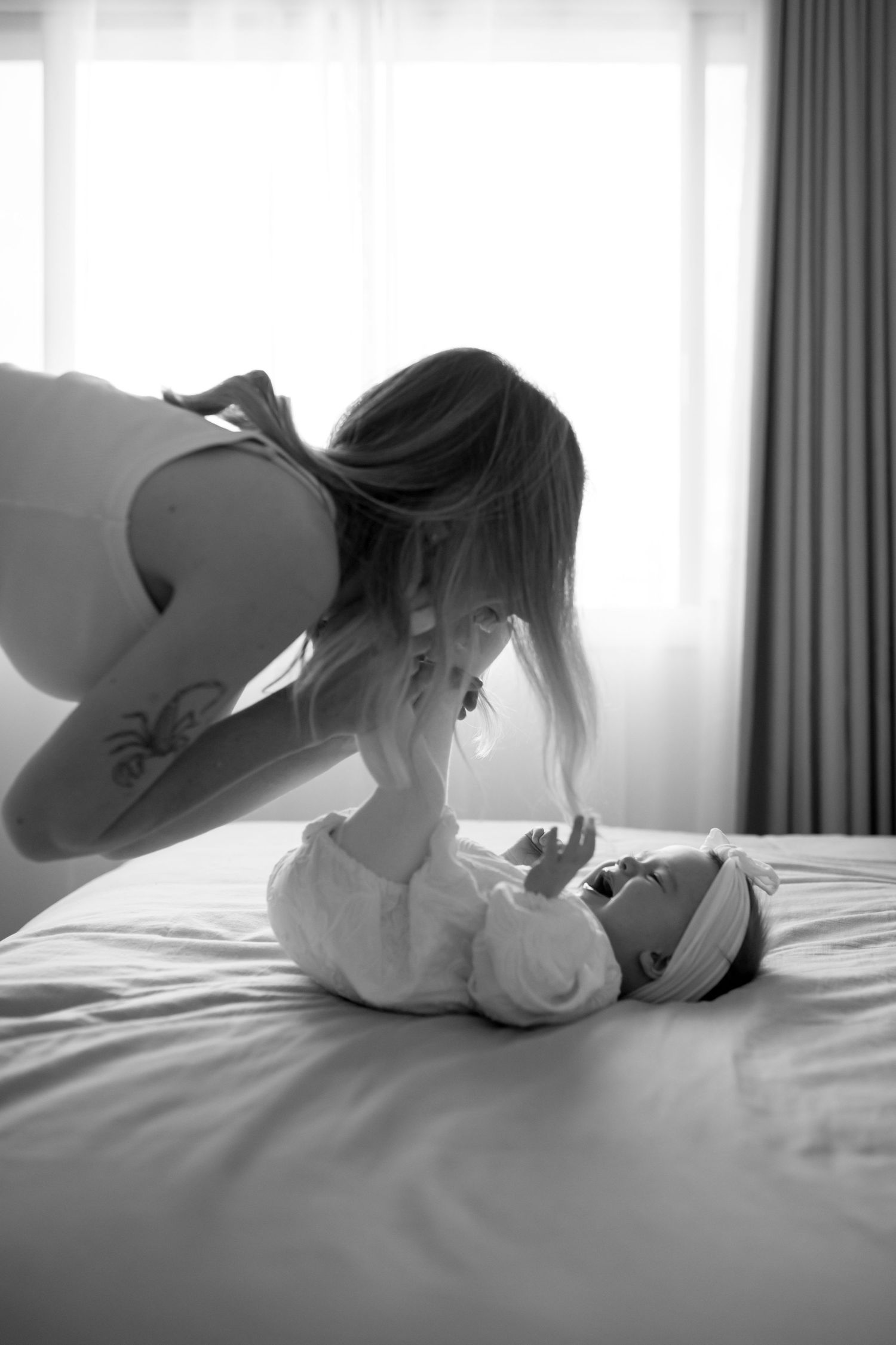 Black and white portrait of tender moments on a bed with soft lighting.