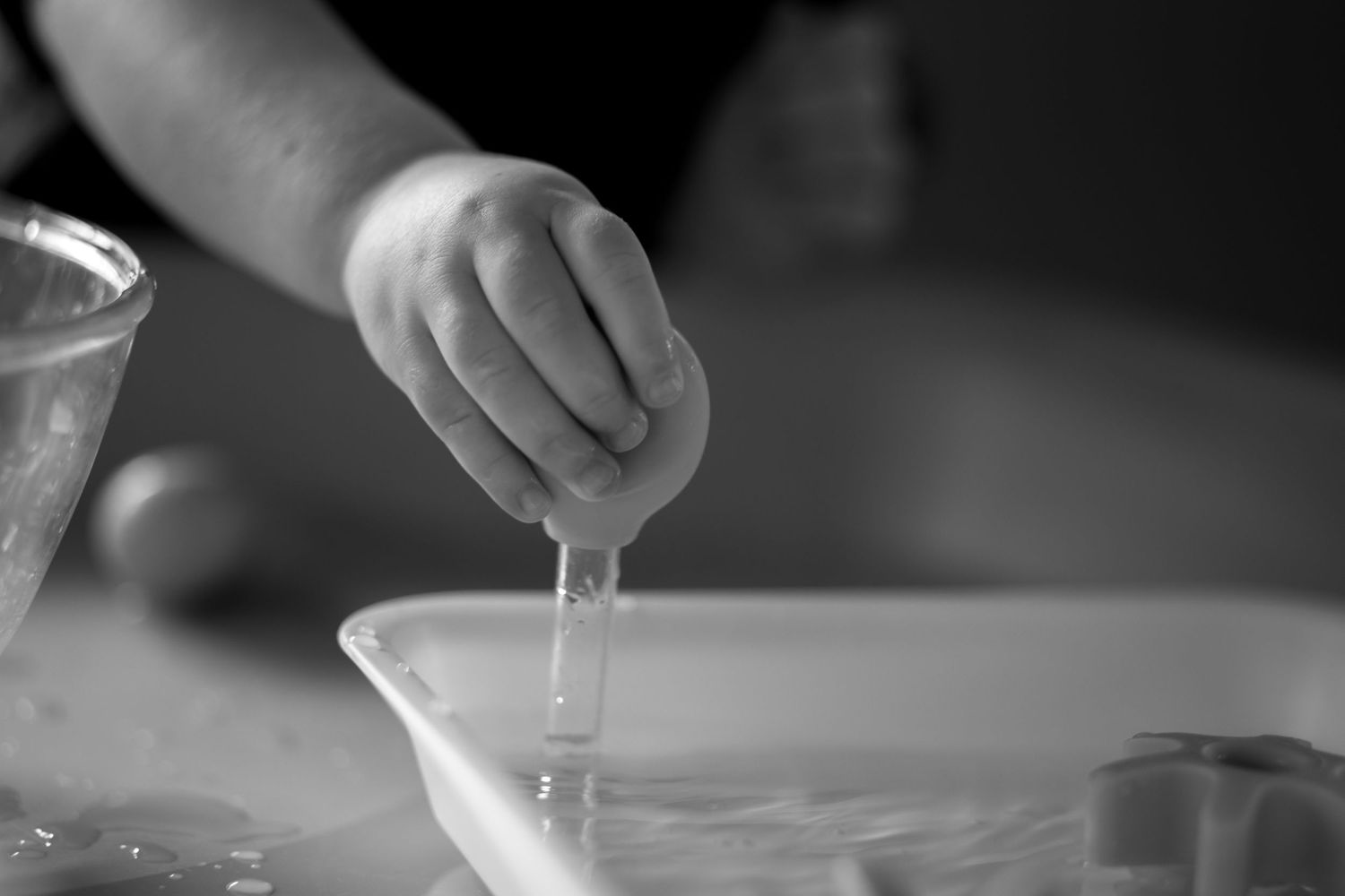 Close-up shots of small hands reaching across a white surface in dramatic lighting.