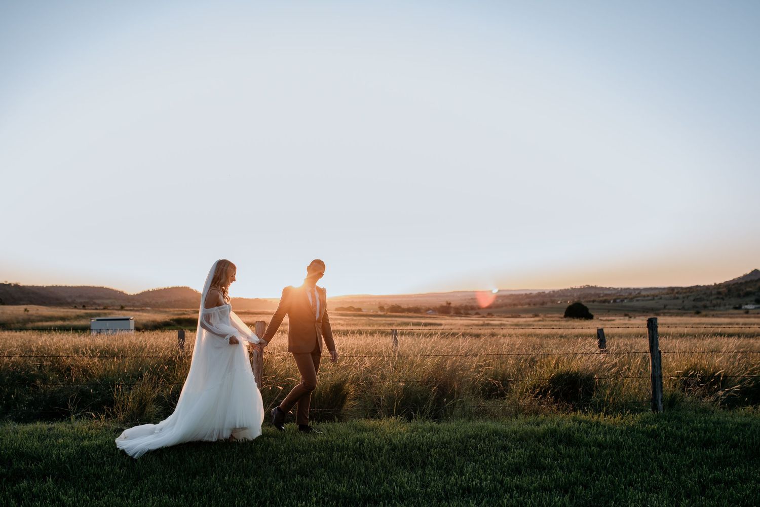 A sunset wedding photo showing silhouettes against a golden field backdrop.
